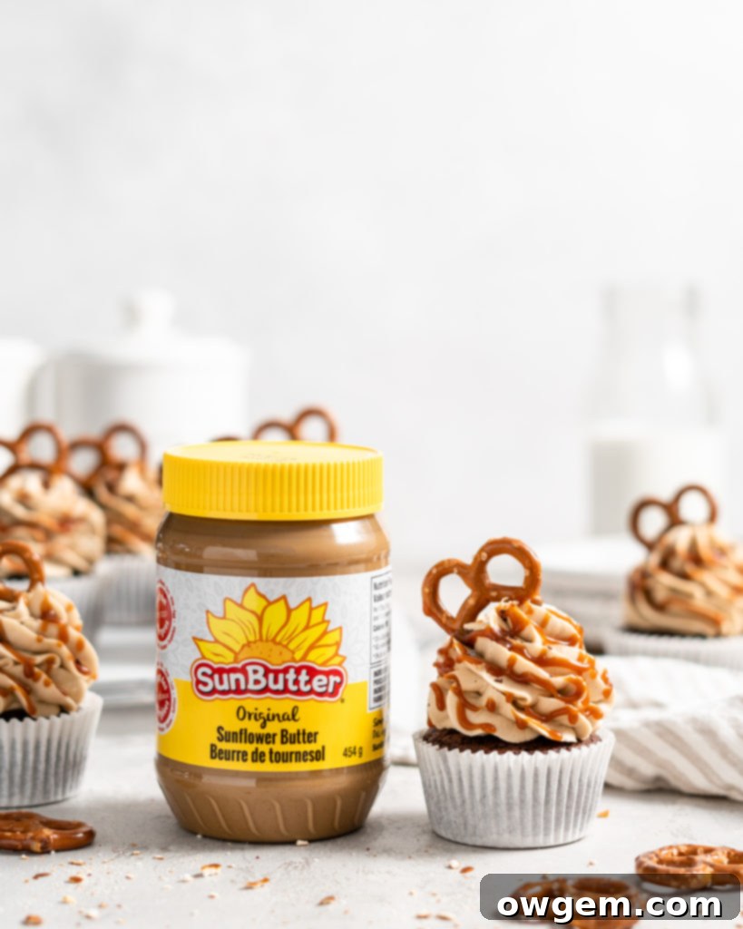 Close-up of an individual chocolate cupcake with a distinct crunchy pretzel base, lavishly frosted with creamy SunButter buttercream, ready for garnishing and serving.