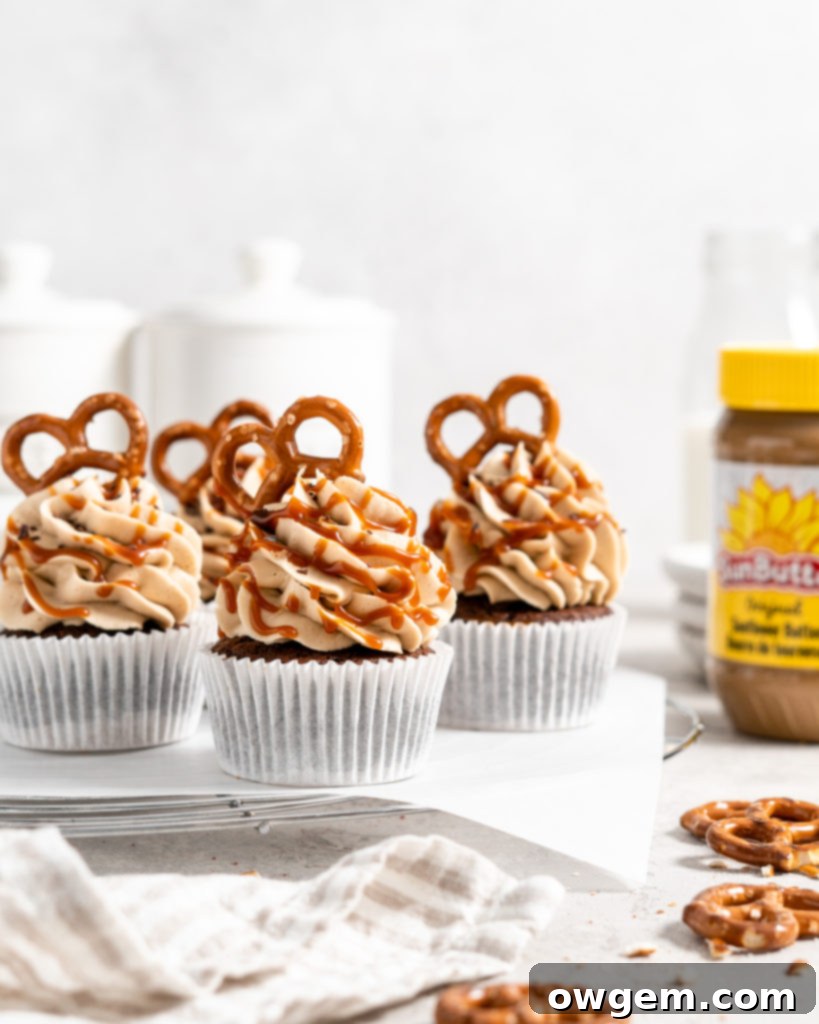 A perfectly piped swirl of creamy SunButter buttercream frosting on a moist chocolate cupcake, adorned with mini pretzels and a decadent drizzle of caramel sauce, highlighting the intricate textures.
