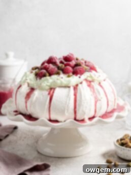 Thick fluffy pavlova topped with whipped pistachio white chocolate ganache and fresh raspberry curd