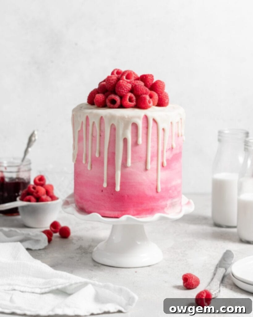 Pink Raspberry Layer Cake with white chocolate drip. Topped with fresh raspberries