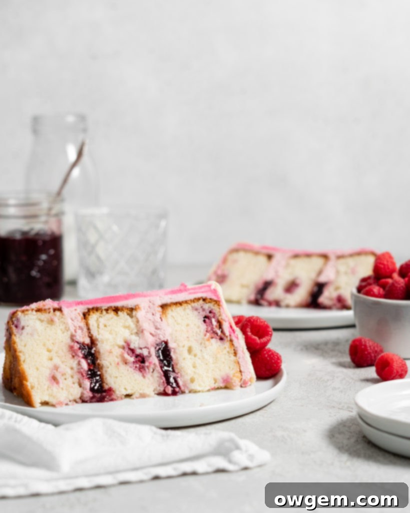 Pink Raspberry Layer Cake with white chocolate drip. Topped with fresh raspberries and filled with jam