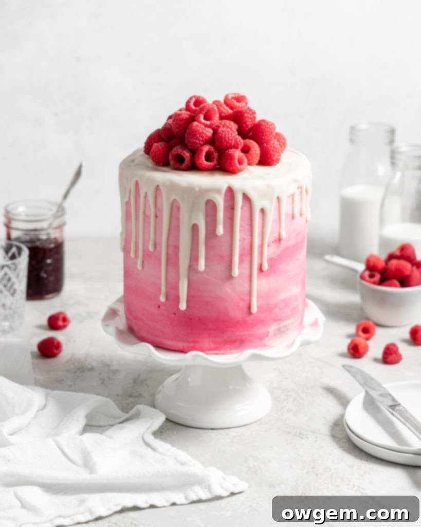 Pink Raspberry Layer Cake with white chocolate drip. Topped with fresh raspberries