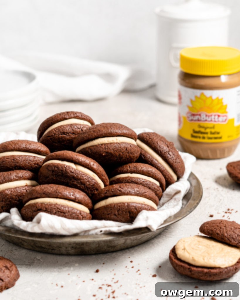 Two chocolate whoopie pies filled with creamy SunButter buttercream on a white plate, showcasing the soft cookie texture and rich filling.