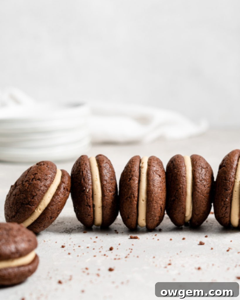 A piping bag dispensing SunButter buttercream onto a chocolate whoopie pie cookie.