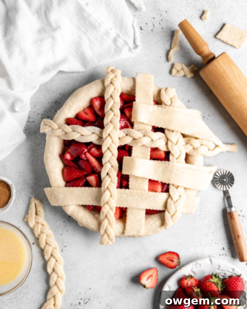 Assembling a lattice top for a strawberry pie, showing interwoven dough strips.