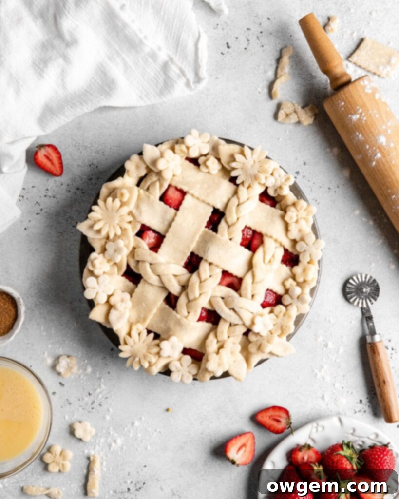 Lattice strawberry pie cooling on a wire rack after baking, showing golden crust and thick filling.