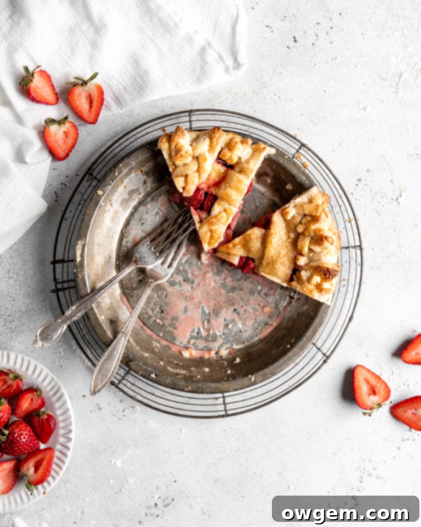 Close-up of a perfectly baked strawberry pie slice, showcasing the vibrant red, thick filling and a golden, flaky crust.