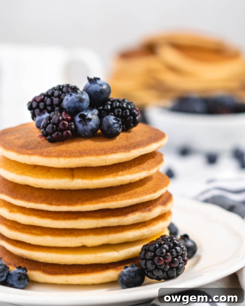 Fluffy Golden Buttermilk Pancakes stacked high, topped with fresh berries