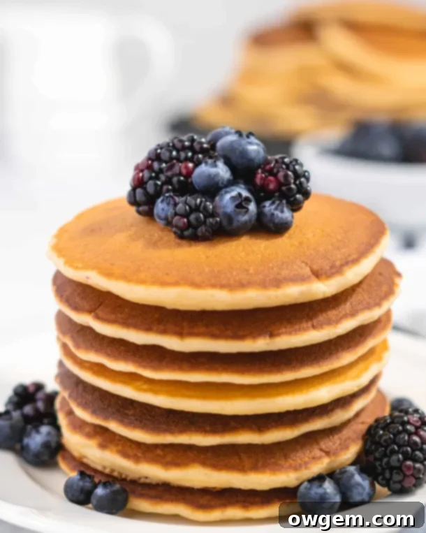 Fluffy Golden Buttermilk Pancakes stacked high, topped with fresh berries