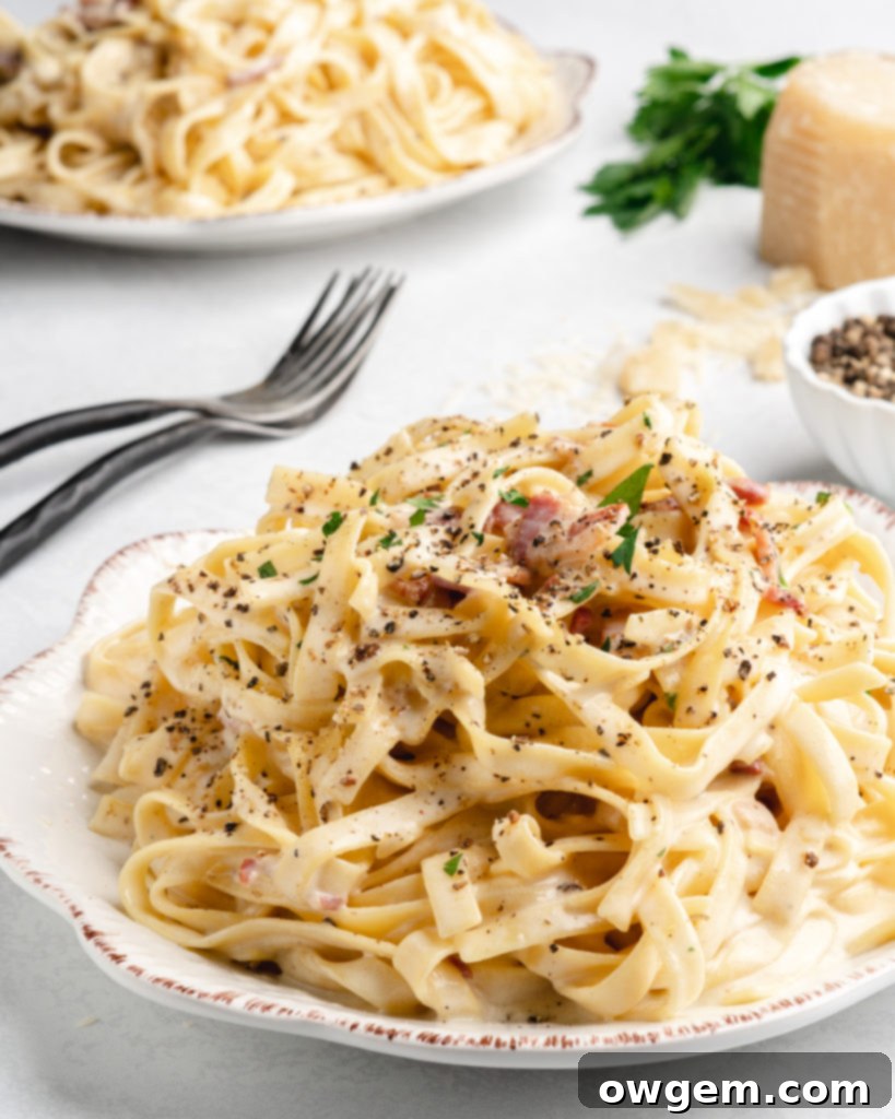 Creamy pasta carbonara is topped with fresh parsley and crispy pancetta