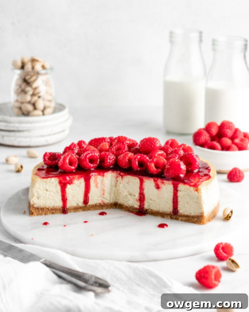 Creamy and rich pistachio cheesecake topped with raspberry sauce and fresh juicy raspberries