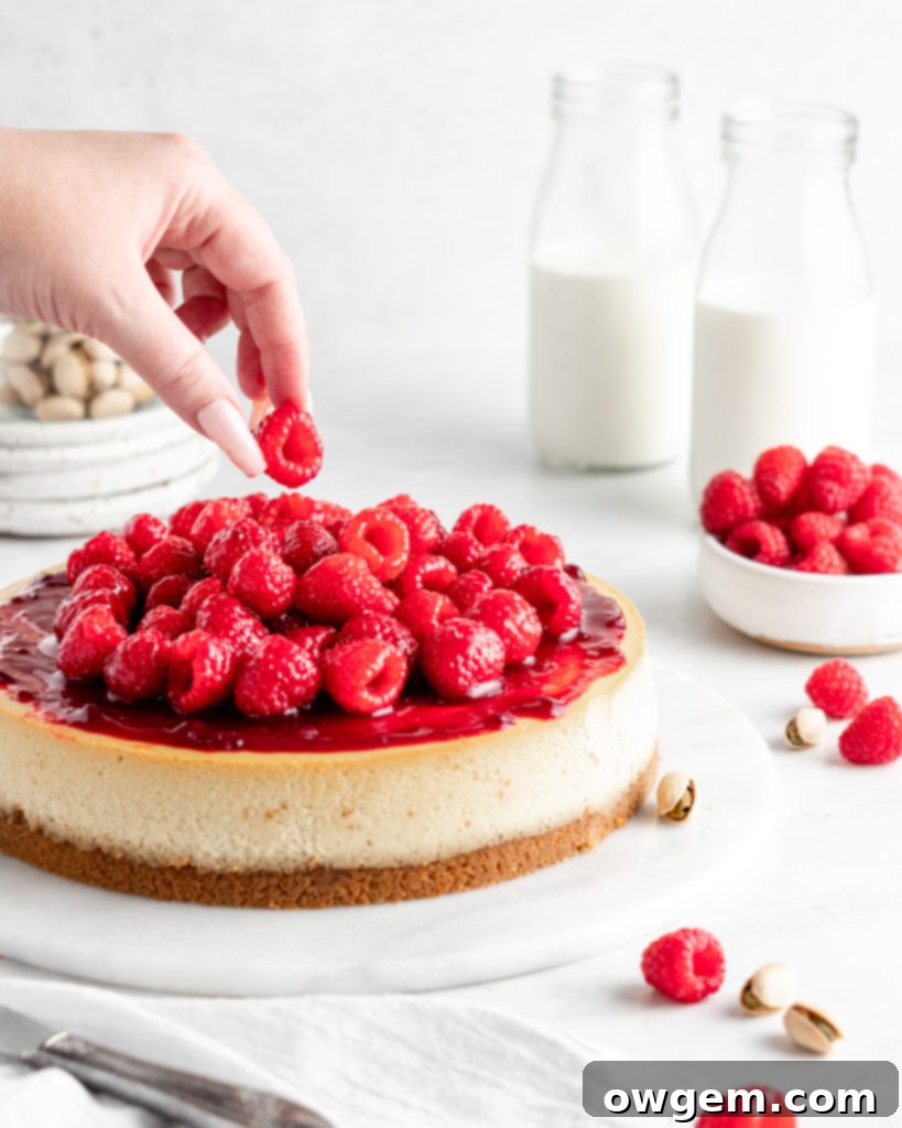 Creamy and rich pistachio cheesecake topped with raspberry sauce and fresh juicy raspberries