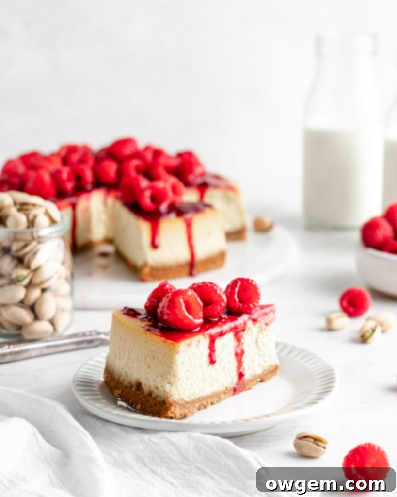 Creamy and rich pistachio cheesecake topped with raspberry sauce and fresh juicy raspberries