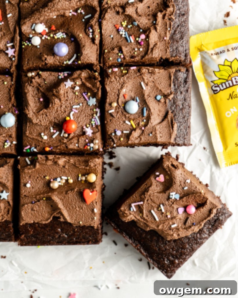 Close-up of SunButter Chocolate Buttercream being spread onto a chocolate sheet cake, adorned with colorful sprinkles.
