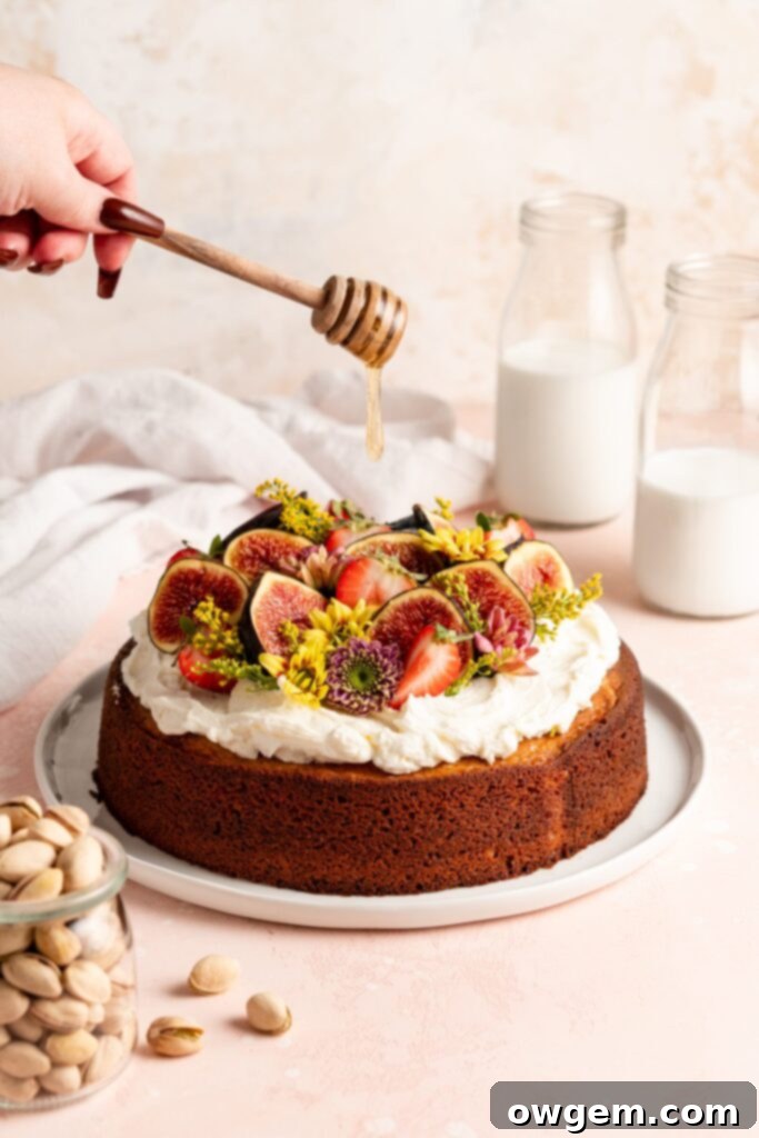 Single layer pistachio cake is topped with creamy honey buttercream and a ton of fresh fruit and flowers