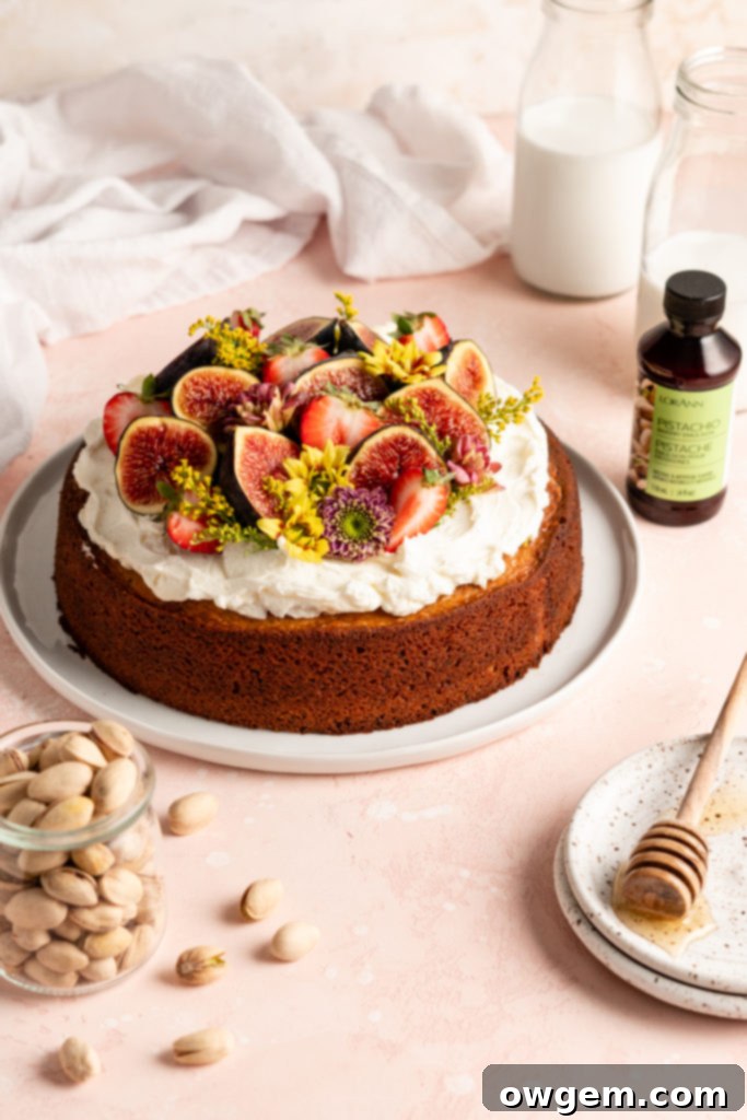 Single layer pistachio cake is topped with creamy honey buttercream and a ton of fresh fruit and flowers