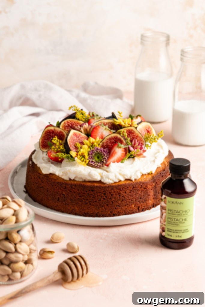 Single layer pistachio cake is topped with creamy honey buttercream and a ton of fresh fruit and flowers