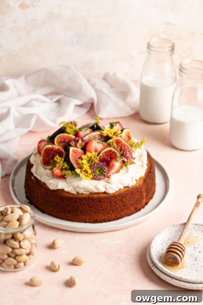 Single layer pistachio cake is topped with creamy honey buttercream and a ton of fresh fruit and flowers