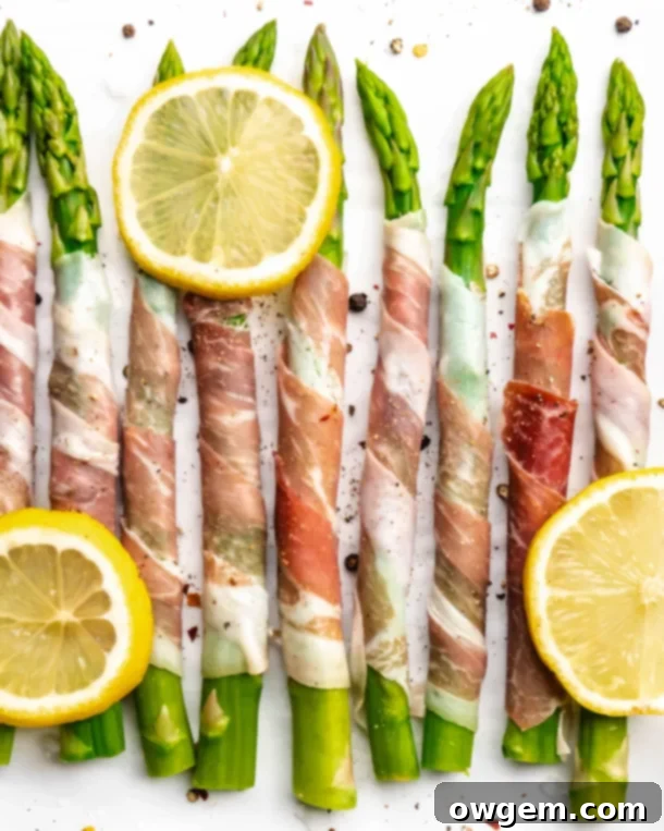 Prosciutto wrapped around fresh green asparagus, topped with lemons, ready to be baked