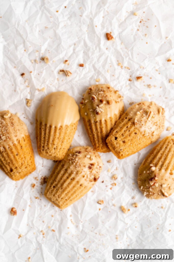 maple chai spiced madeleines dipped in a maple glaze and sprinkled with crushed pecans on a cooling rack
