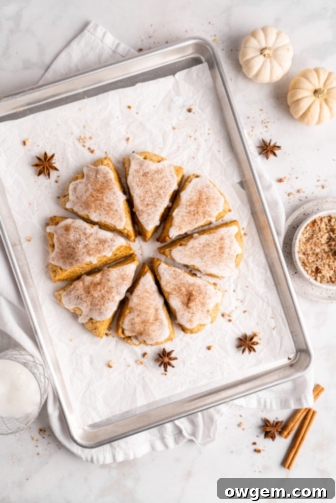 flaky and tender chai pumpkin scones with vanilla glaze, sprinkled with cinnamon and cloves