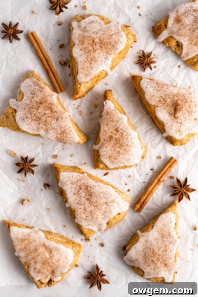 flaky and tender chai pumpkin scones with vanilla glaze, sprinkled with cinnamon and cloves