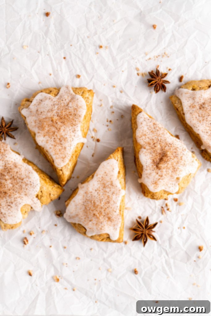 flaky and tender chai pumpkin scones with vanilla glaze, sprinkled with cinnamon and cloves