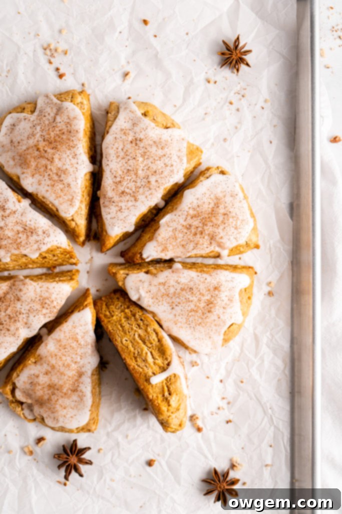 flaky and tender chai pumpkin scones with vanilla glaze, sprinkled with cinnamon and cloves