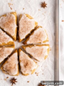 flaky and tender chai pumpkin scones with vanilla glaze, sprinkled with cinnamon and cloves