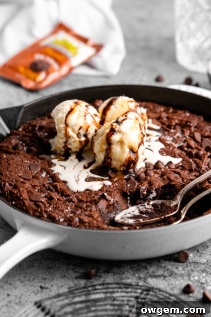 A slice of warm triple chocolate brownie skillet being lifted, showing its fudgy texture