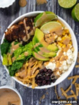 A beautifully presented Earls copycat Santa Fe Chicken Salad, featuring grilled Cajun chicken, fresh greens, corn, black beans, feta, dates, avocado, and crunchy tortilla strips, all dressed in a creamy peanut lime vinaigrette.