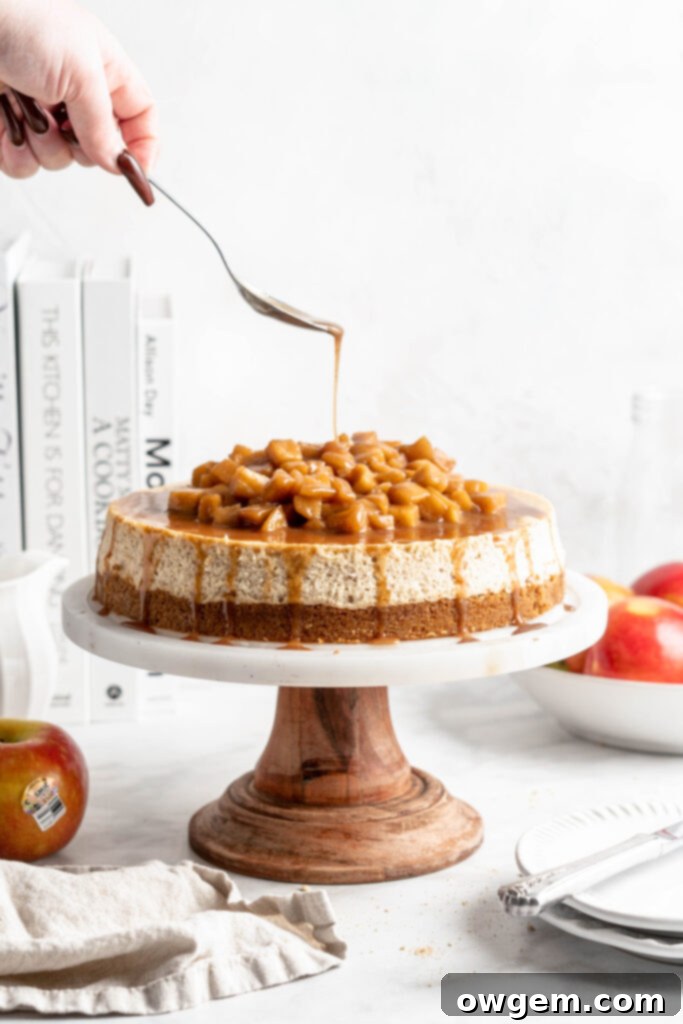 A slice of creamy rich apple spice cheesecake topped with a delicious cinnamon apple compote on a white plate
