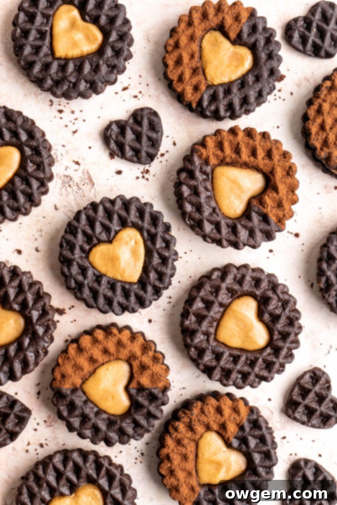 A stack of freshly baked chocolate peanut butter cookie sandwiches, showcasing the intricate heart cutouts and creamy filling.