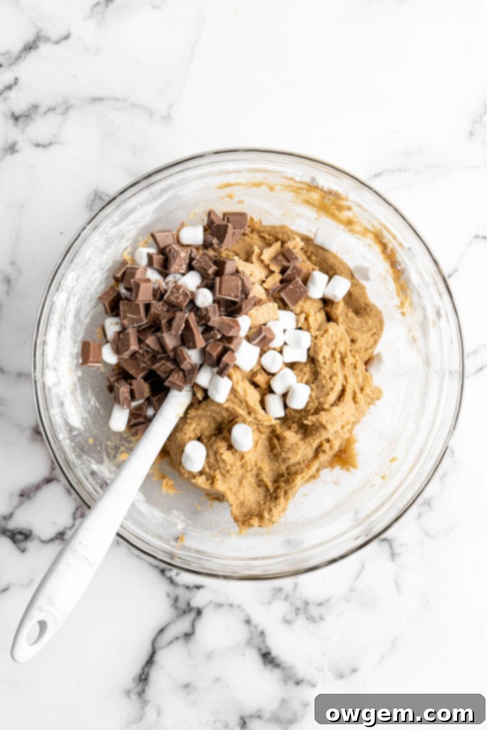 Raw SunButter S'mores cookie dough, generously speckled with chopped chocolate, mini marshmallows, and crushed graham crackers, ready for baking.