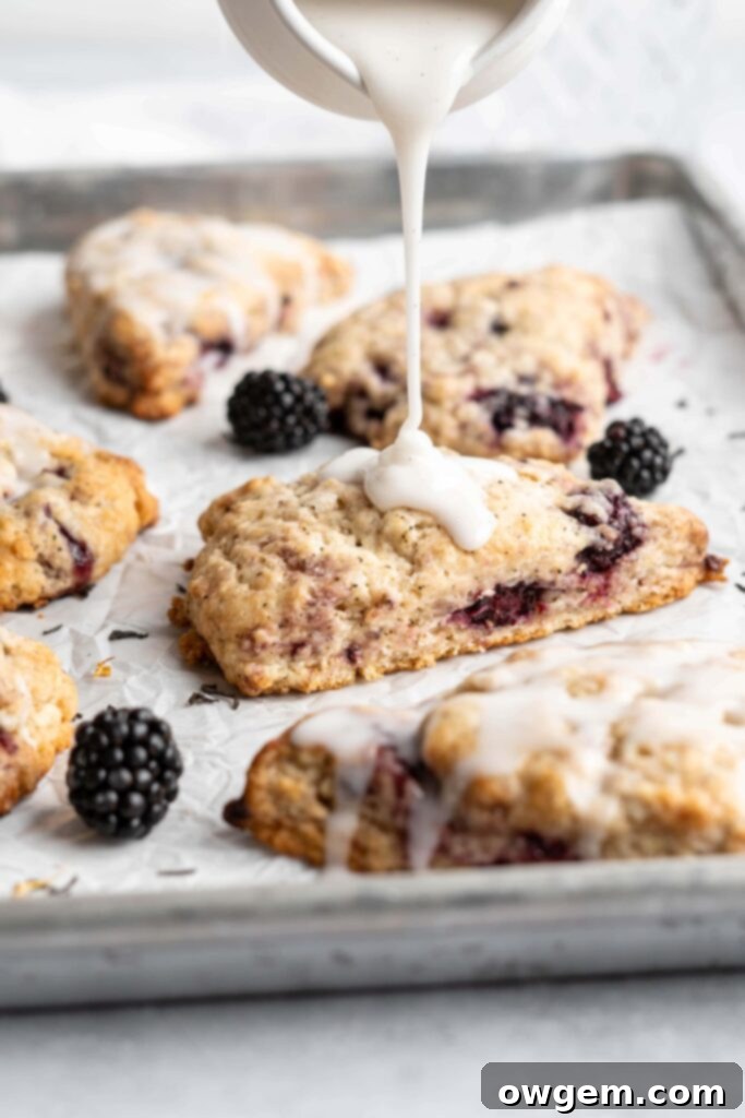 Glaze drizzling over freshly baked blackberry earl grey scones