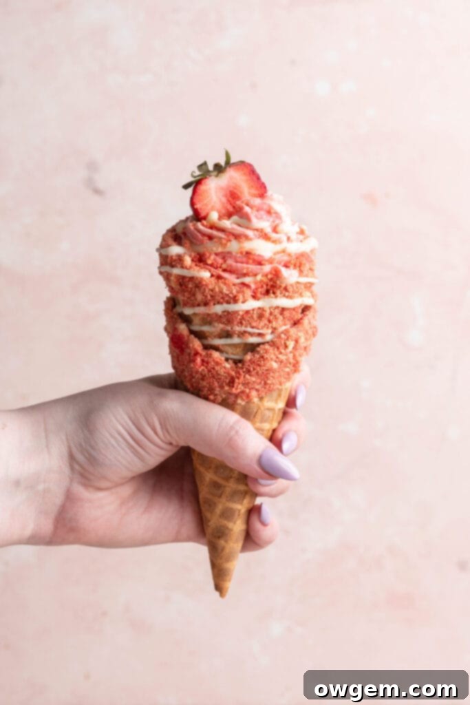 strawberry crunch cheesecake cone being held by hand.