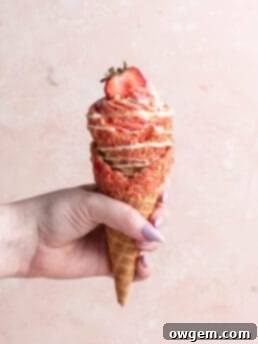 strawberry crunch cheesecake cone being held by hand.