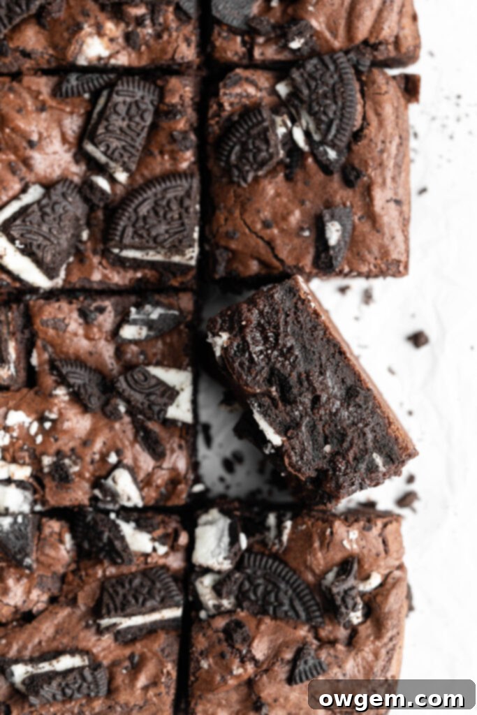 Crinkly top brownies with Oreos on top, one brownie turned on its side, showcasing the rich, fudgy texture.