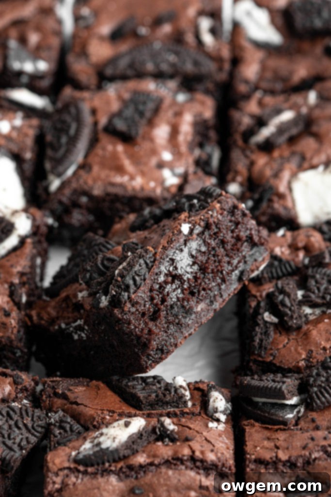 Close-up of crinkly top brownies with whole and chopped Oreos scattered on top.