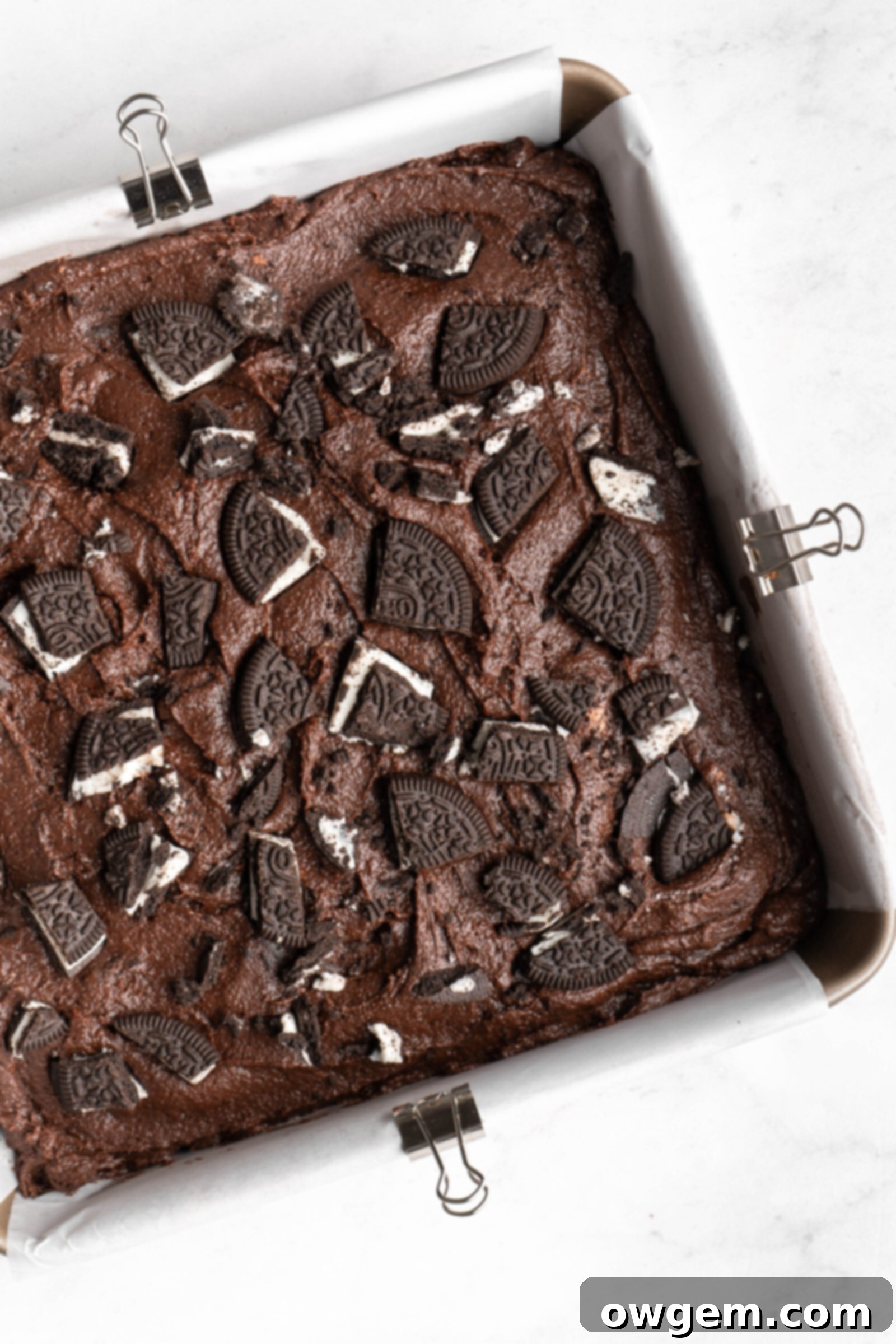 Oreo SunButter Brownie batter spread evenly in a prepared baking pan, topped with more Oreos.