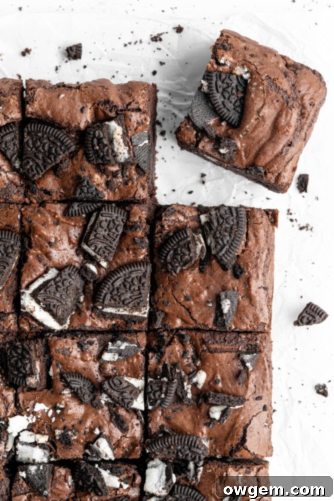 Stack of fudgy crinkly top brownies with Oreos on top, glistening.