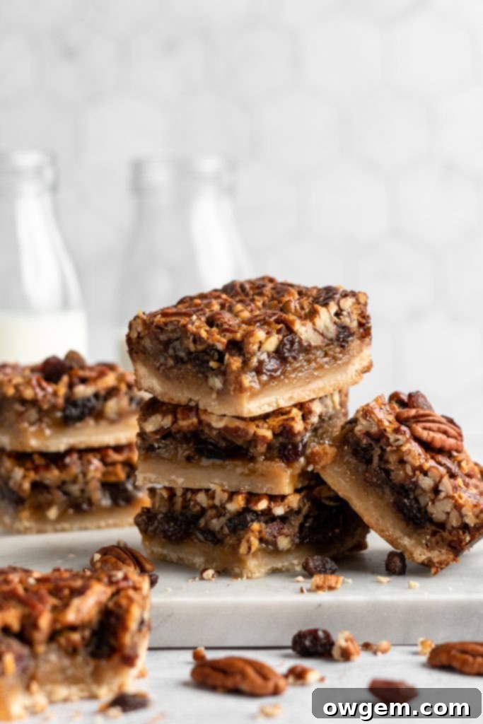 Stack of Pecan pie bars with raisins, garnished with powdered sugar
