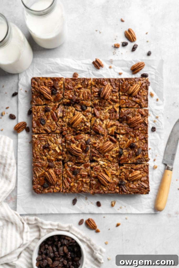 Close-up of a pecan pie bar, showcasing the gooey filling, pecans, and raisins on a shortbread crust