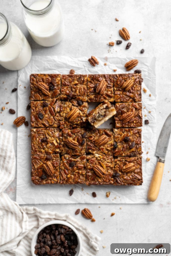 A slice of pecan pie bar with raisins on a white plate