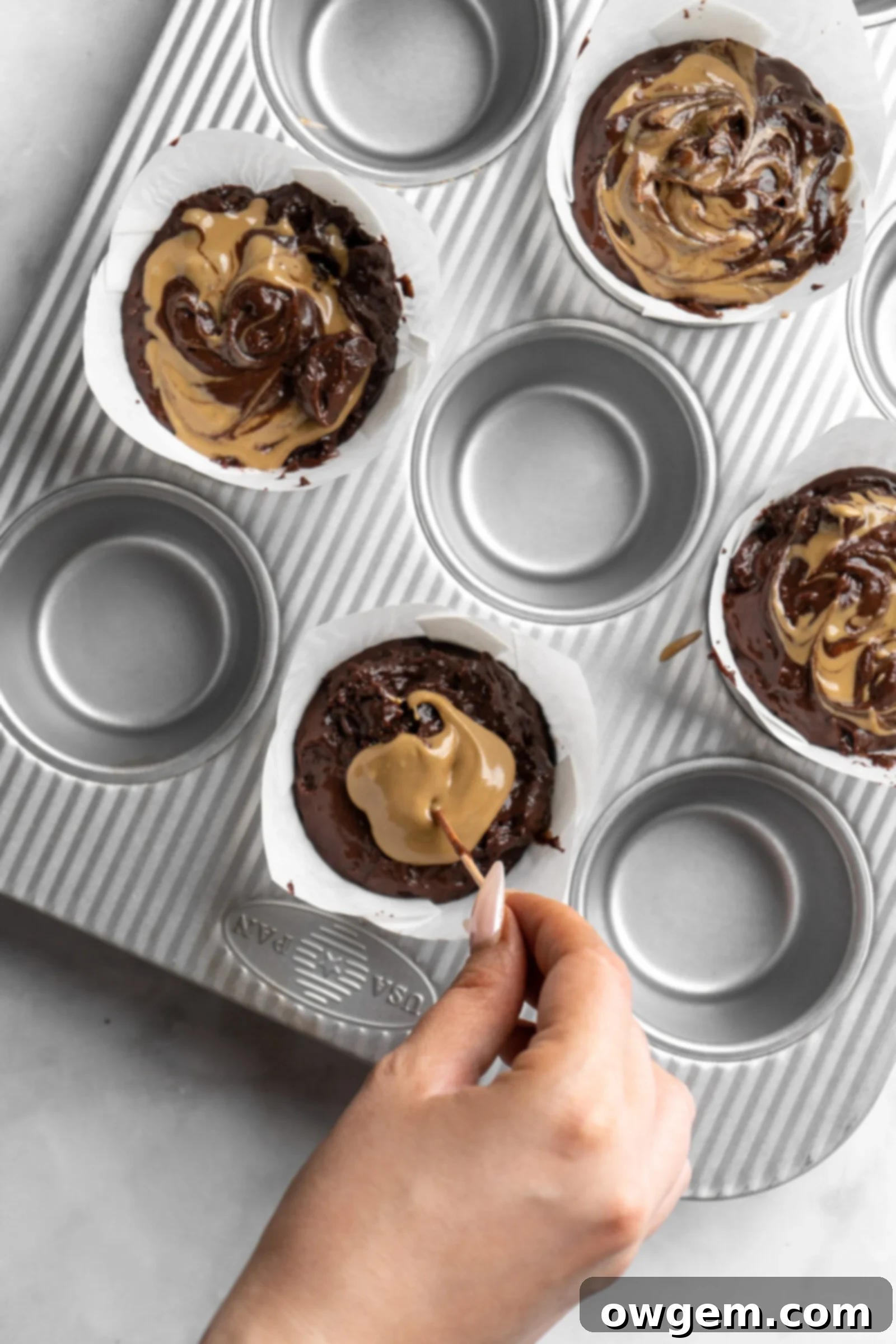 Swirling Sunbutter into bakery style double chocolate chip muffin batter with a skewer.