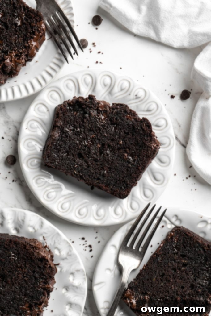 Two generous slices of rich, fudgy triple chocolate zucchini bread displayed on white plates, ready to be served and enjoyed.