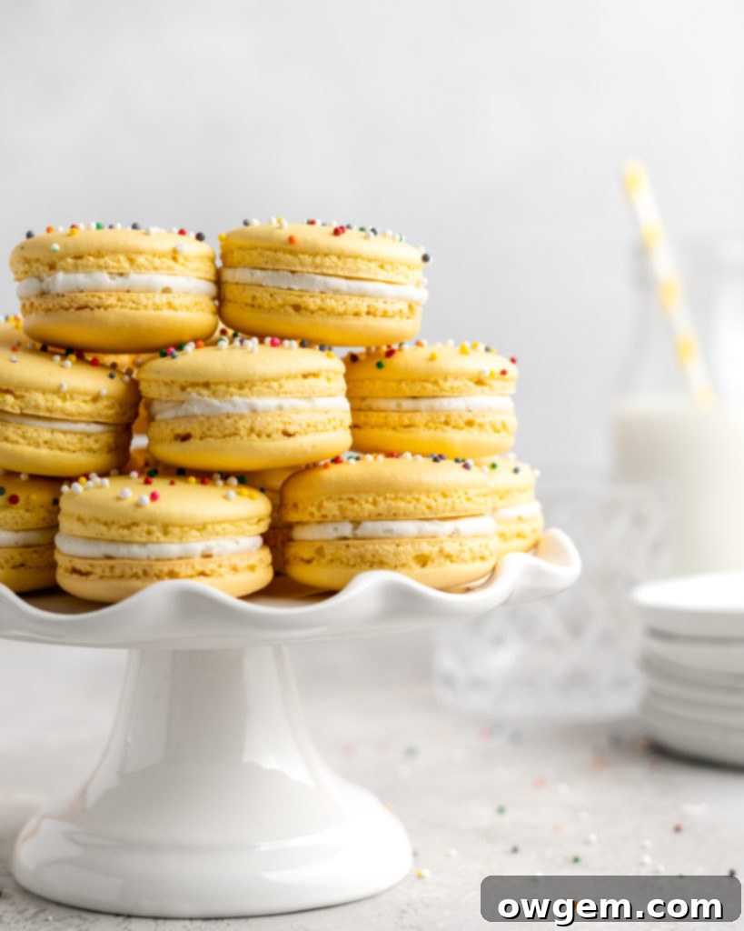A stack of perfectly filled yellow macarons with rainbow sprinkles, ready for maturation, emphasizing the importance of allowing them to sit.