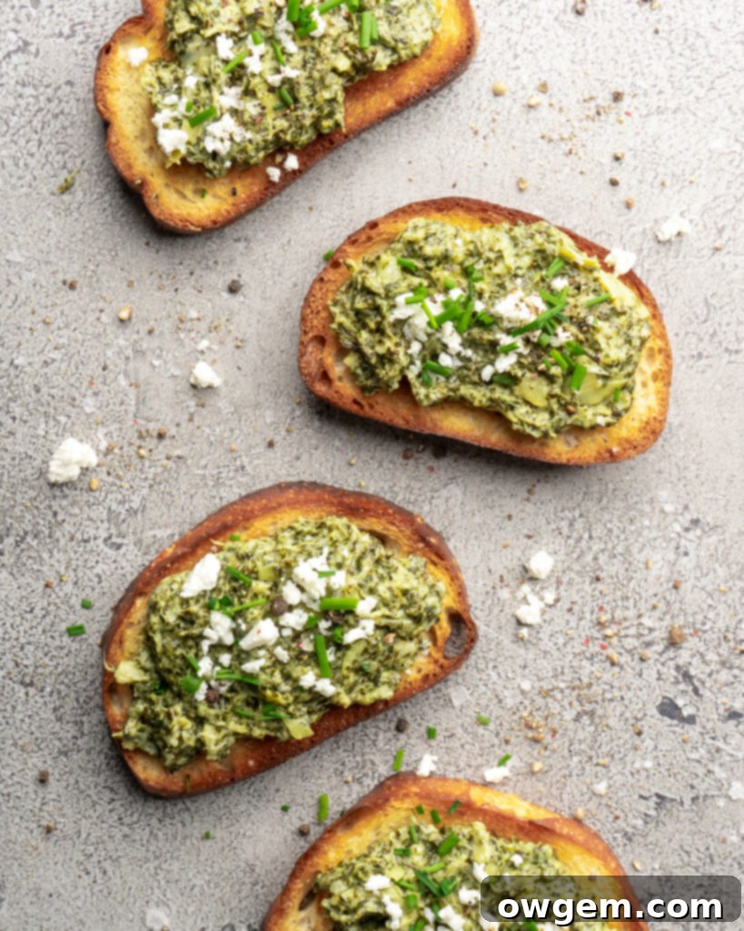 Creamy bright green spinach dip and artichoke dip, topped with feta cheese and chives and served warm