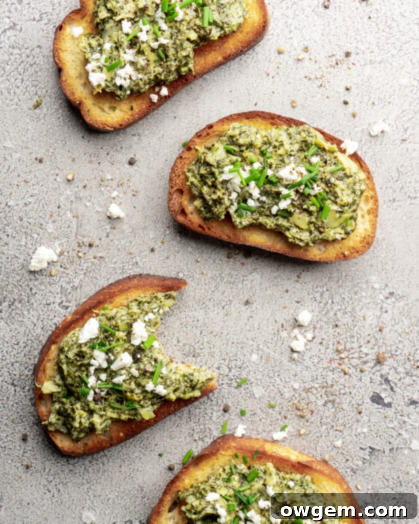 Creamy bright green spinach dip and artichoke dip, topped with feta cheese and chives and served warm