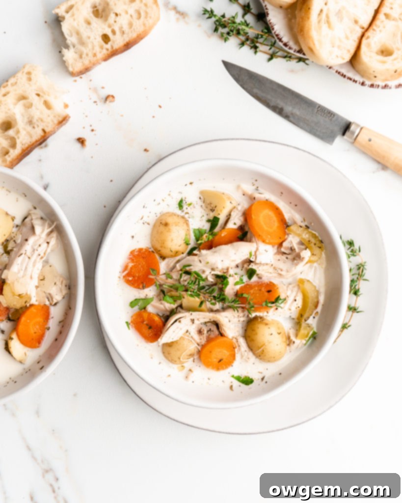 A steaming bowl of rich, creamy chicken and potato soup, garnished with fresh herbs and crumbled bacon, ready to be enjoyed.